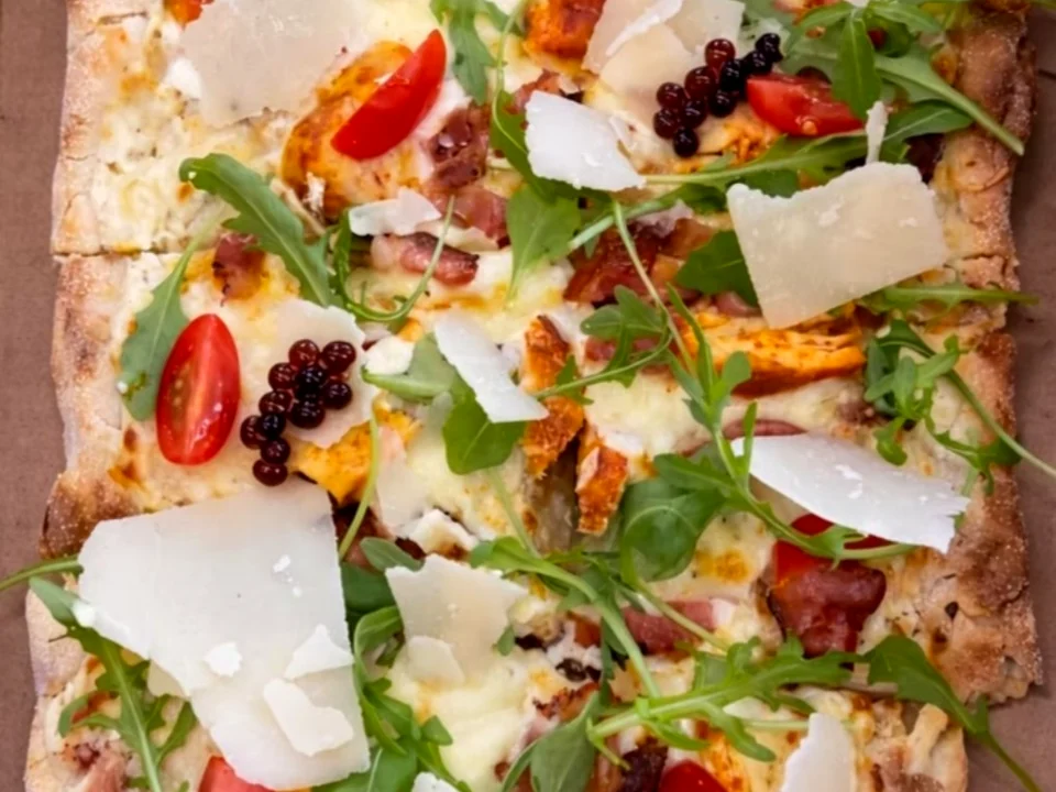 Pinsa gourmande du César avec poulet, tomates, roquette et parmesan